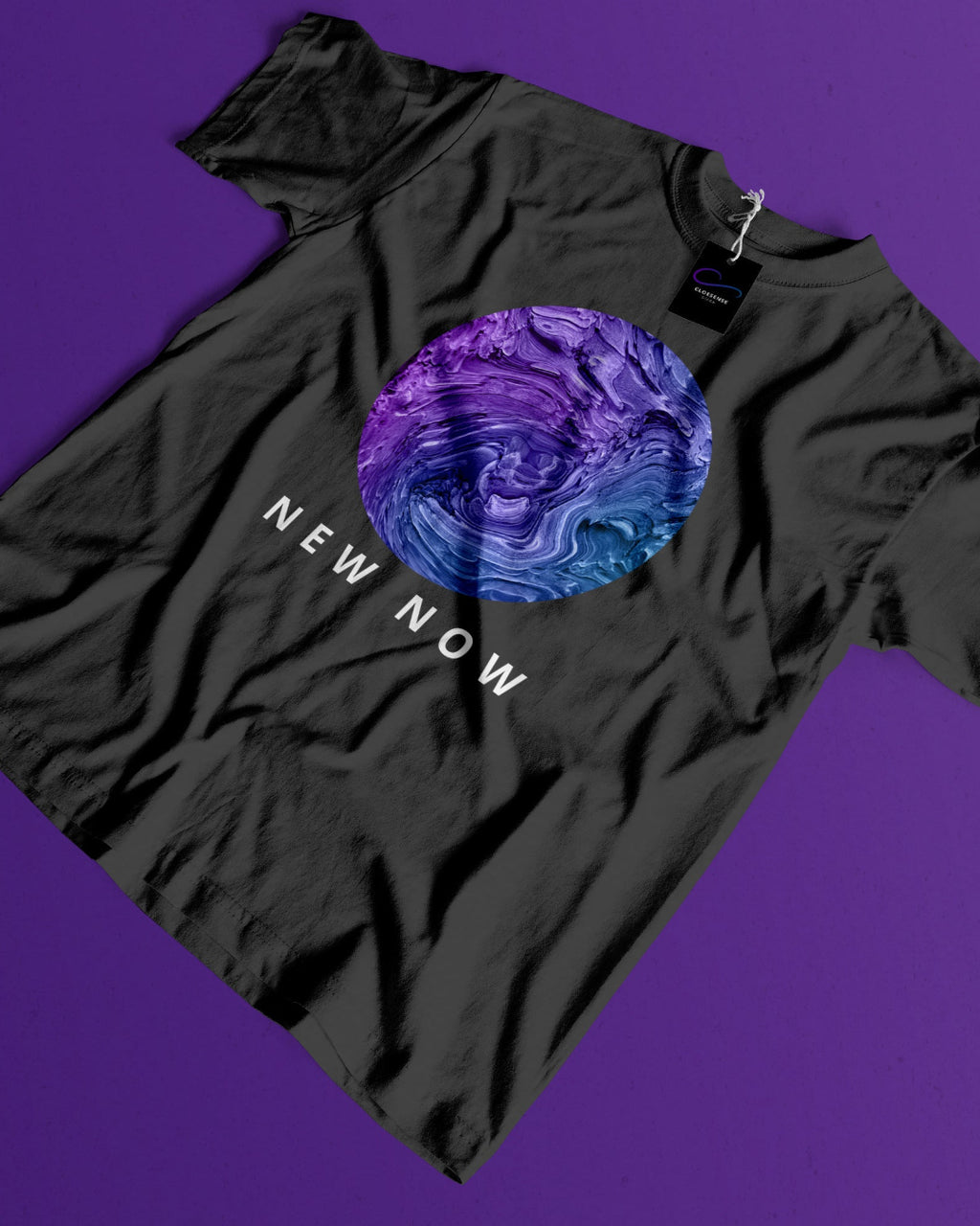 A black short-sleeve t-shirt laid flat on a solid purple background, featuring a circular graphic in purple and blue tones with the text 'NEW NOW' printed below it.