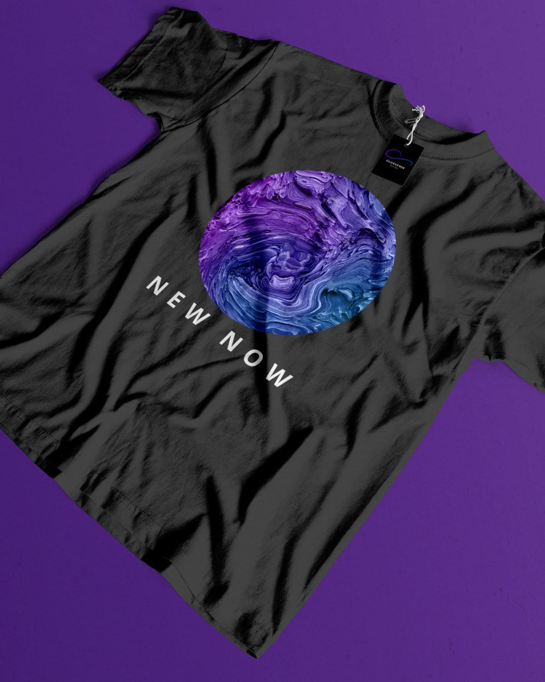 A black short-sleeve t-shirt laid flat on a solid purple background, featuring a circular graphic in purple and blue tones with the text 'NEW NOW' printed below it.