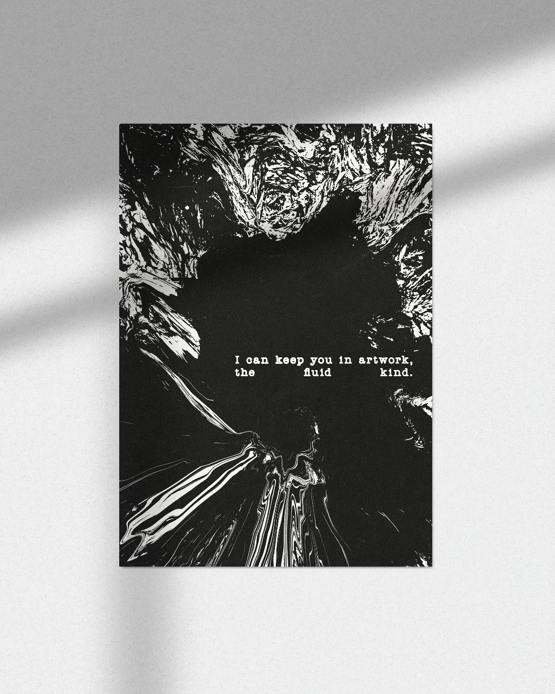 A black and white art print featuring a textured, cracked surface with a small white quote in the center, displayed on a light gray wall with soft window shadows.